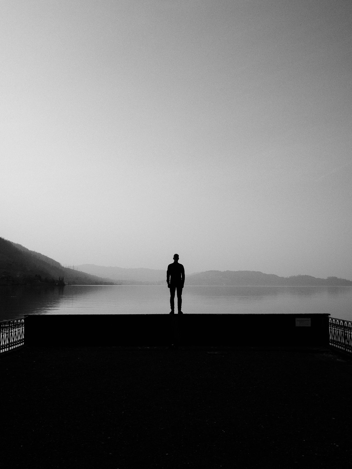 Man standing alone by the water at dusk, reflecting on burnout and overwhelm