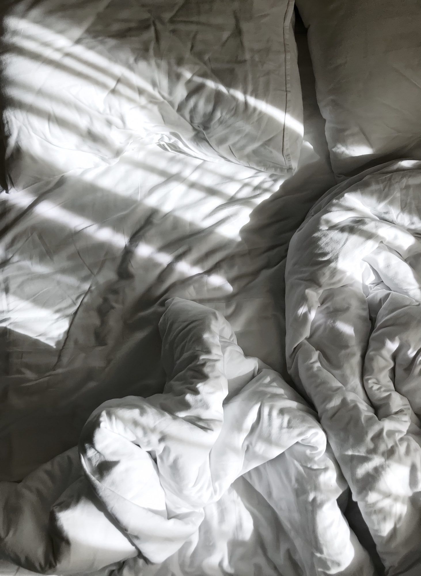 Sunlight falling across rumpled bed sheets in the morning
